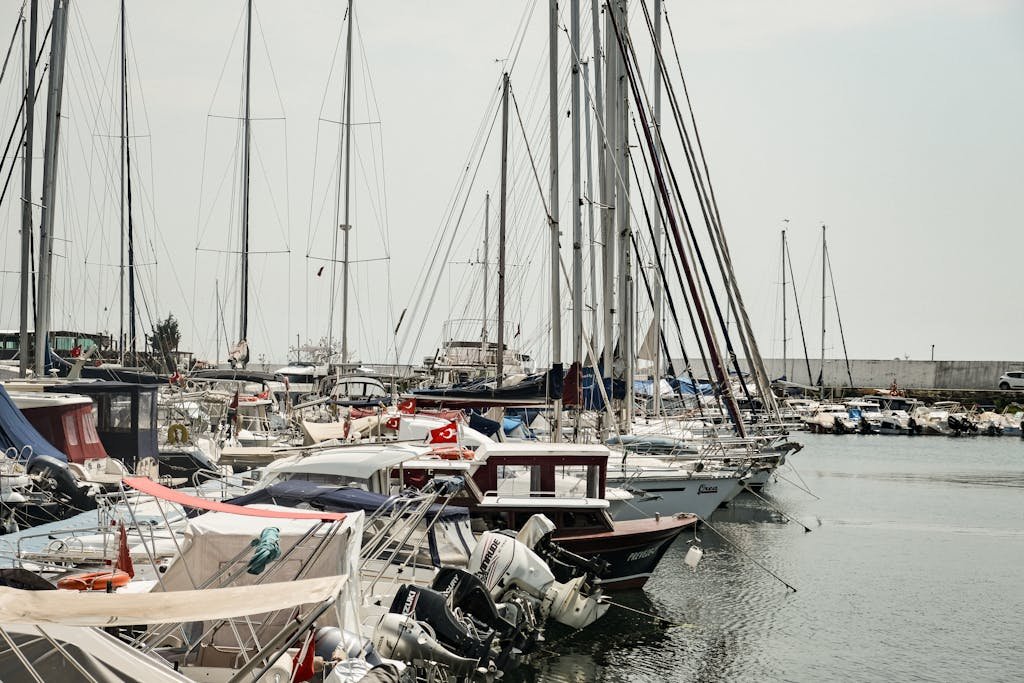 A busy marina in Istanbul with sailboats and yachts docked under a calm sky.